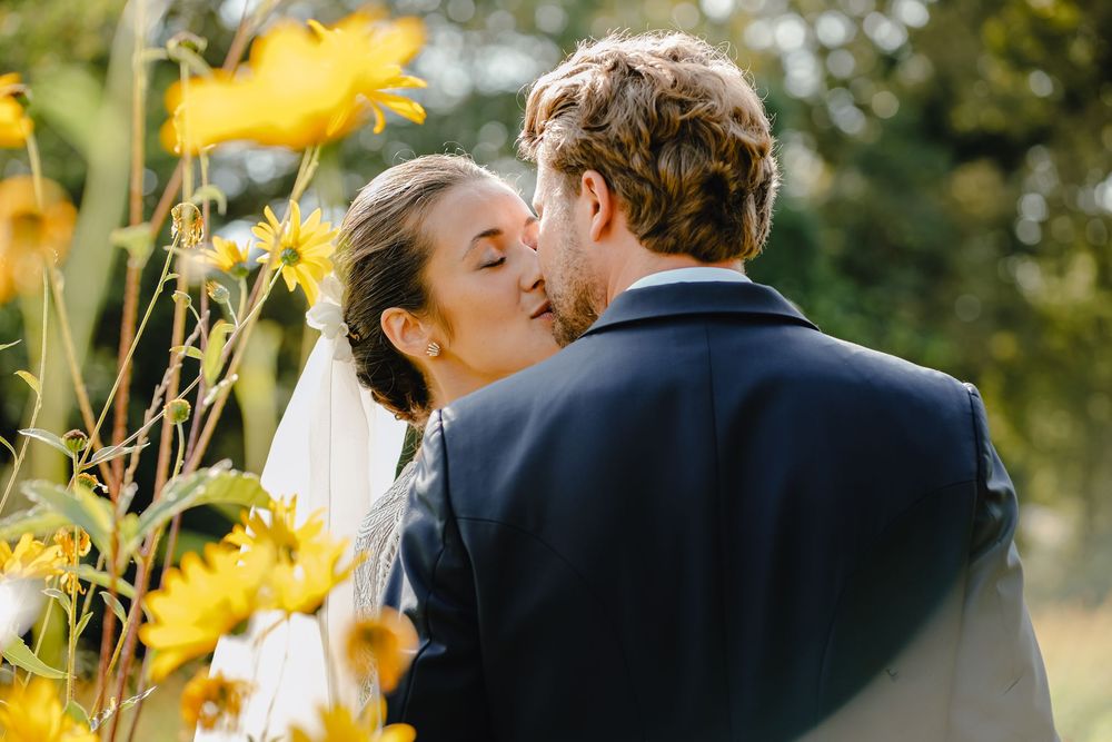 Romantic moment among yellow wildflowers during outdoor wedding celebration.