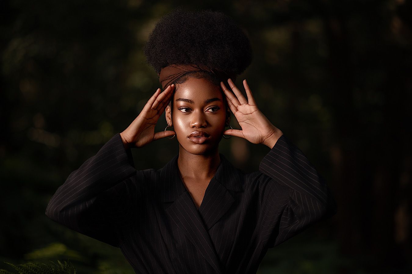 Person wearing black clothing poses dramatically against dark background in artistic portrait series.