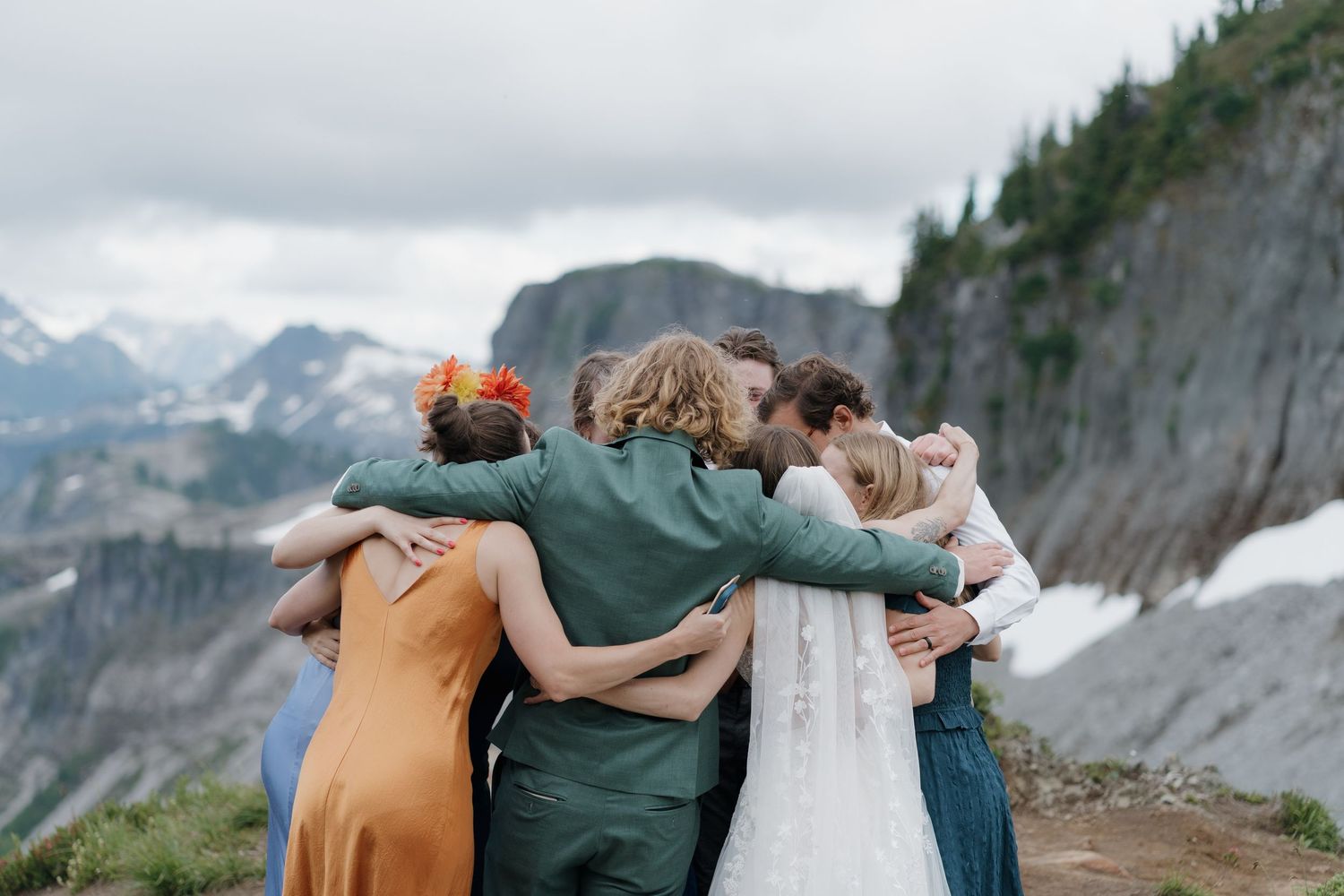 A couple shares an intimate moment while surrounded by majestic mountain peaks in a scenic outdoor landscape.