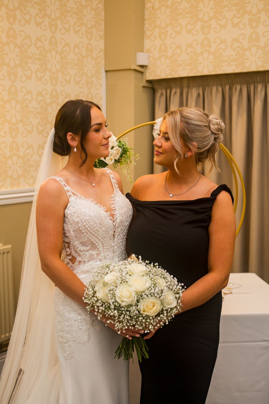 Indoor wedding portrait with elegant cream wallpaper and gold circular backdrop.