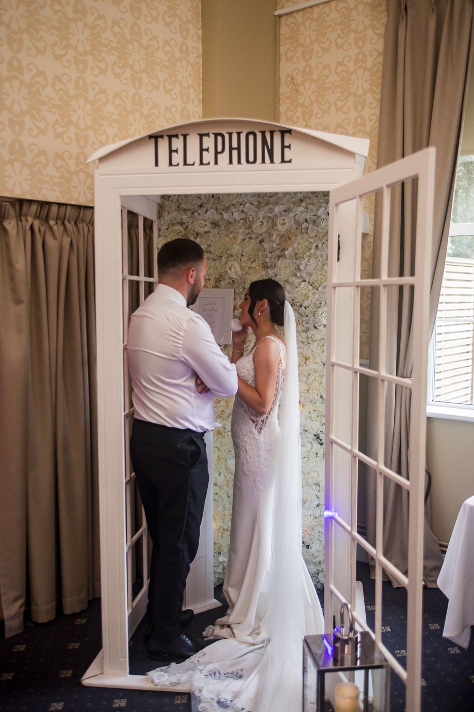 Couple interacting near vintage telephone booth in formal attire.
