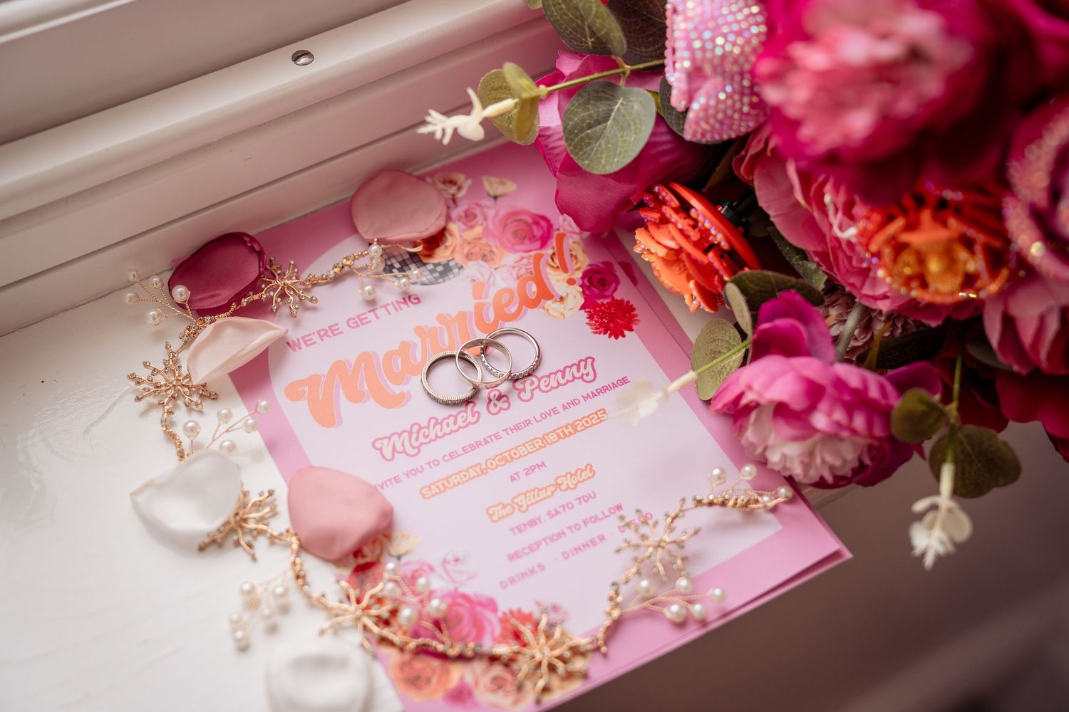 Pink floral wedding invitation suite with delicate roses and romantic details arranged on wooden surface.