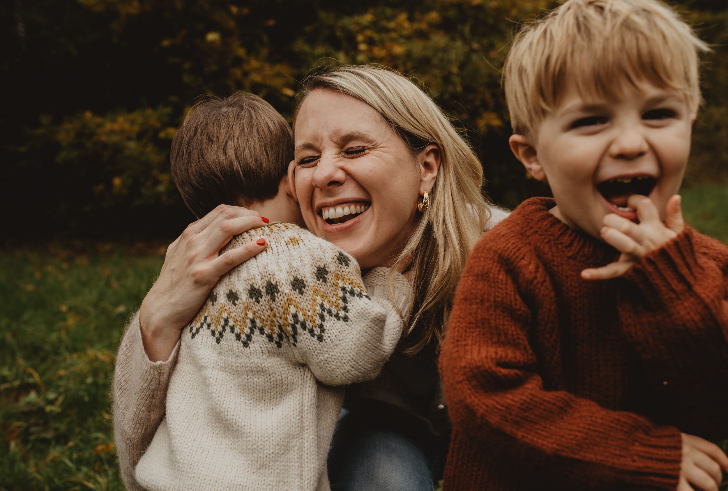 Group of people wearing cozy autumn sweaters laughing and enjoying a candid moment outdoors.