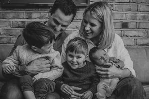 Black and white photo of a happy family sharing joyful moments together on a brick wall background.