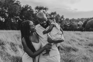 Black and white photo series showing a couple embracing and laughing together in a grassy outdoor field.