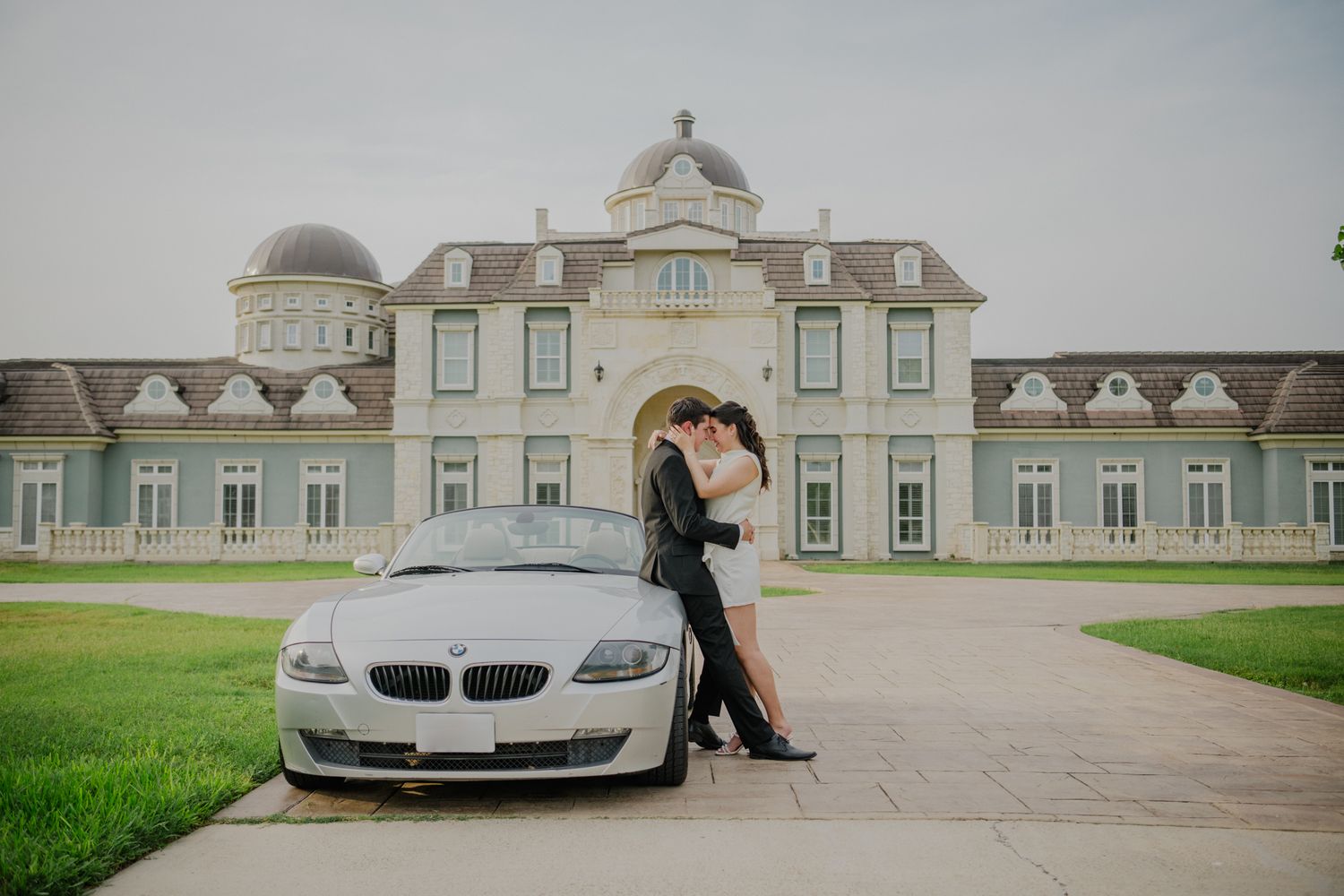 An elegant wedding venue with classic architecture and a BMW luxury car parked in front of a grand estate.
