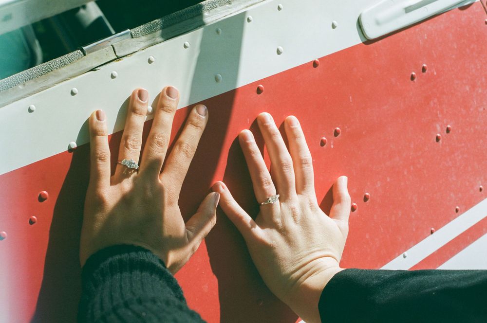 Hands reach out to touch the red and white exterior of an aircraft in close-up detail.