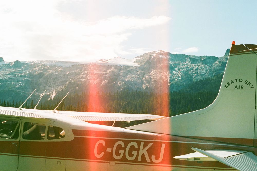 Small aircraft parked at a mountain airfield with snow-capped peaks in the background.