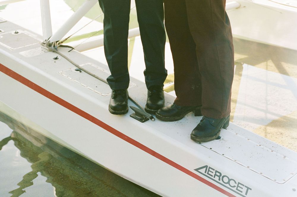 A person's feet stand on a white surface with red lines, showing part of what appears to be a floor marking or guide.