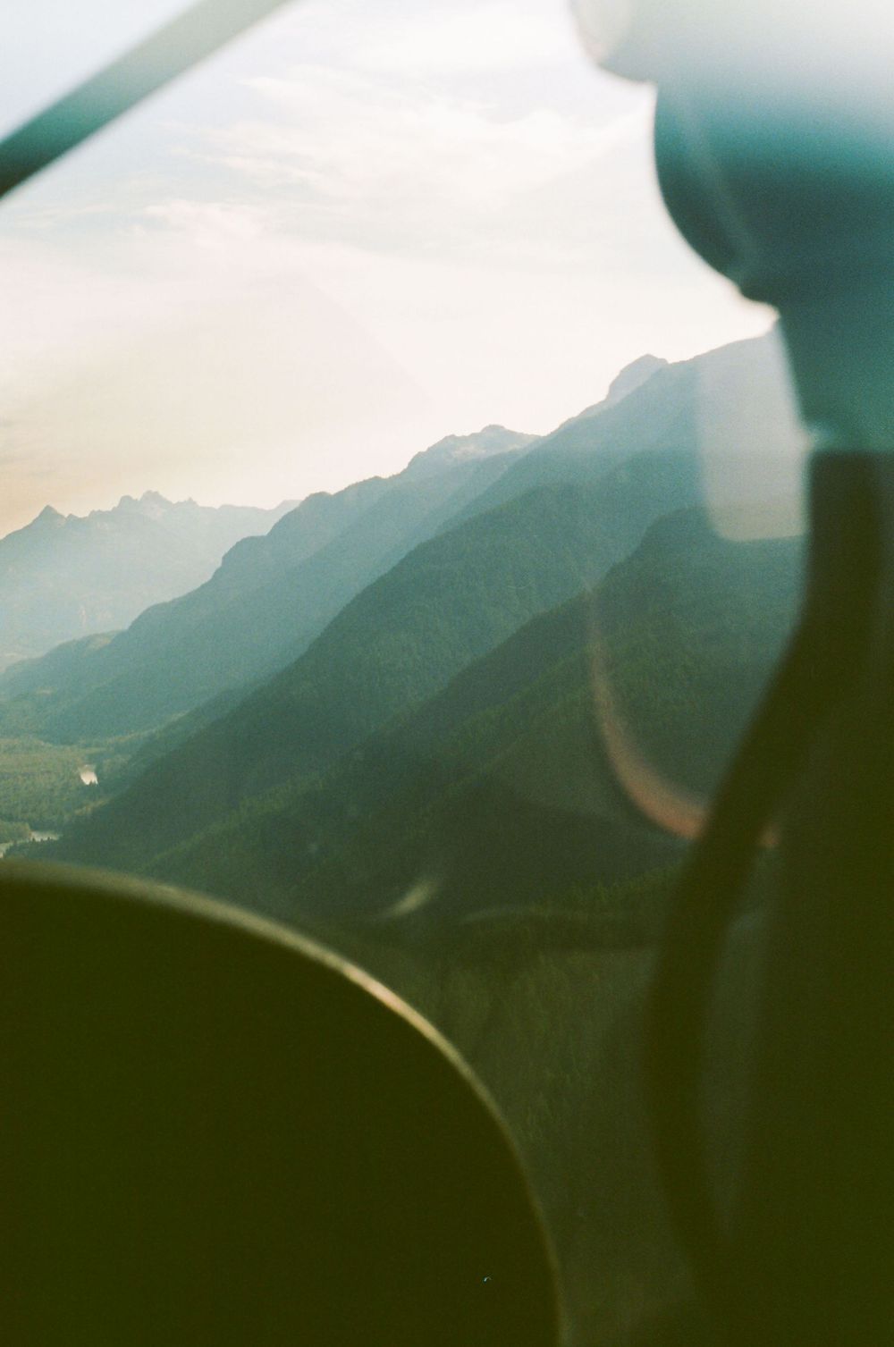 Aerial view of misty mountain peaks through an aircraft window during flight.