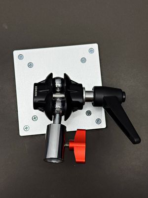 Close-up view of a black camera mounting bracket with adjustable clamp and red lever against a dark background.