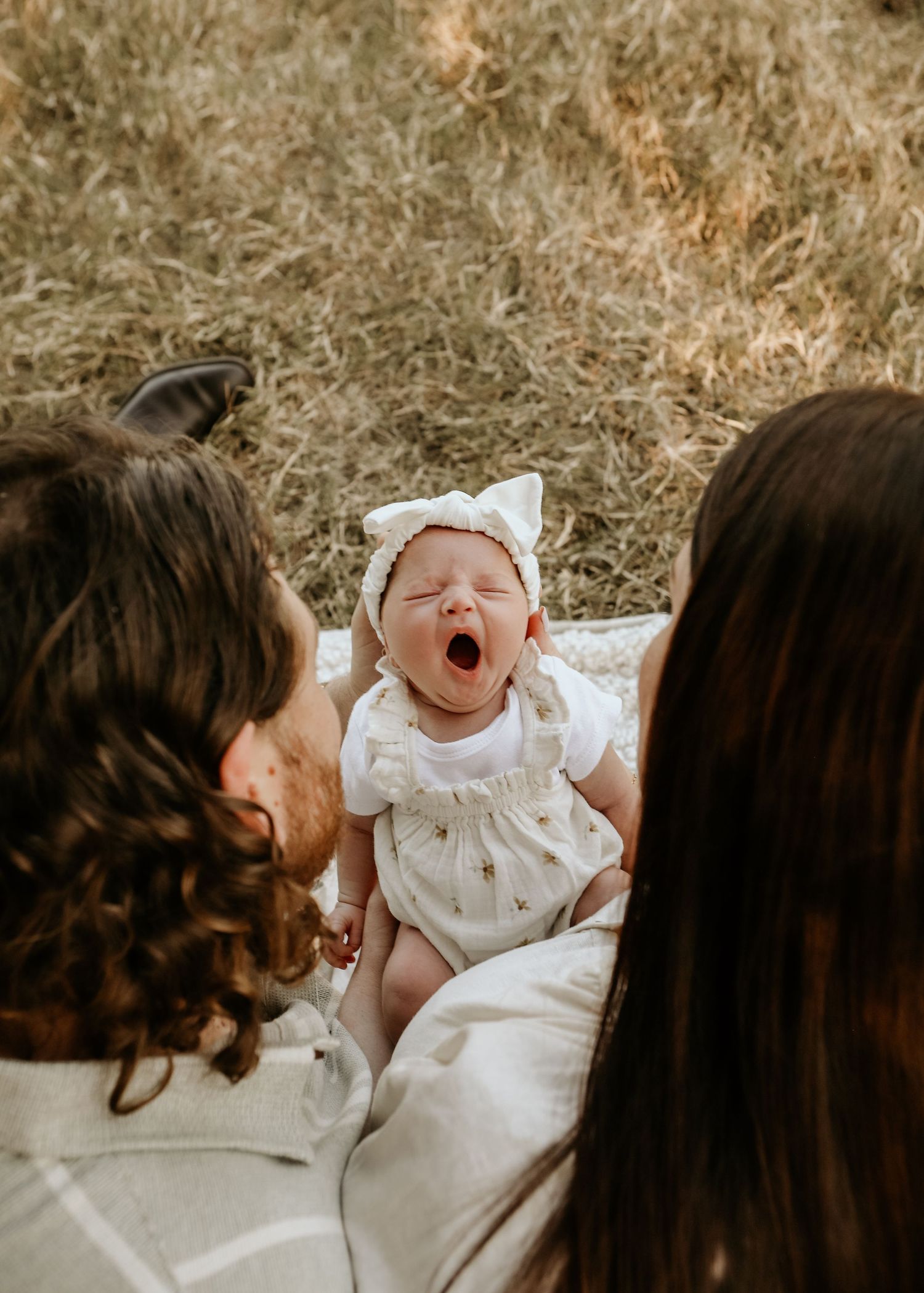 A heartwarming sequence of candid moments showing a baby in white clothing being held and interacting with family members outdoors.