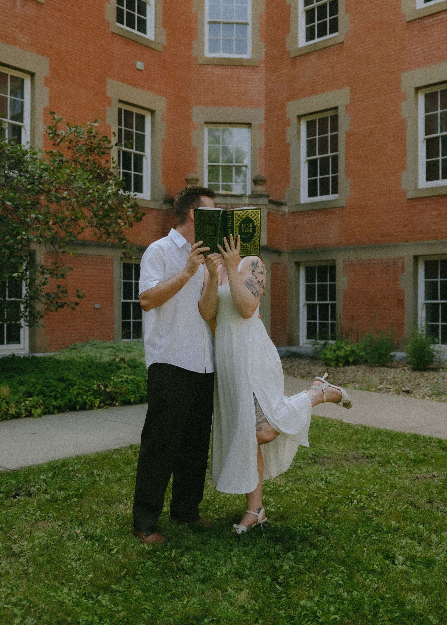 A couple poses for a series of romantic wedding photos outside a brick building with white windows.