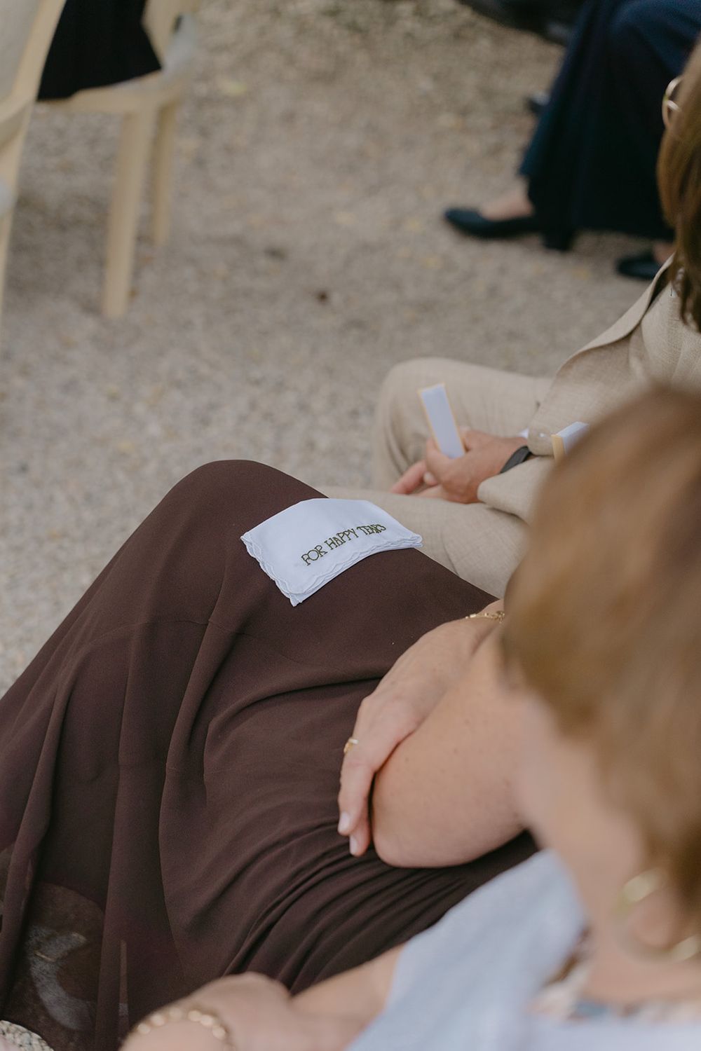 Close-up detail of brown fabric and hands during a wedding ceremony.