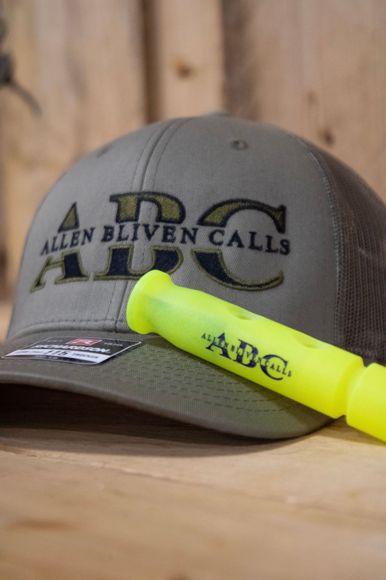 Close-up detail shots of a gray trucker hat with Allen Eliven Calls branding and neon yellow accent strap.