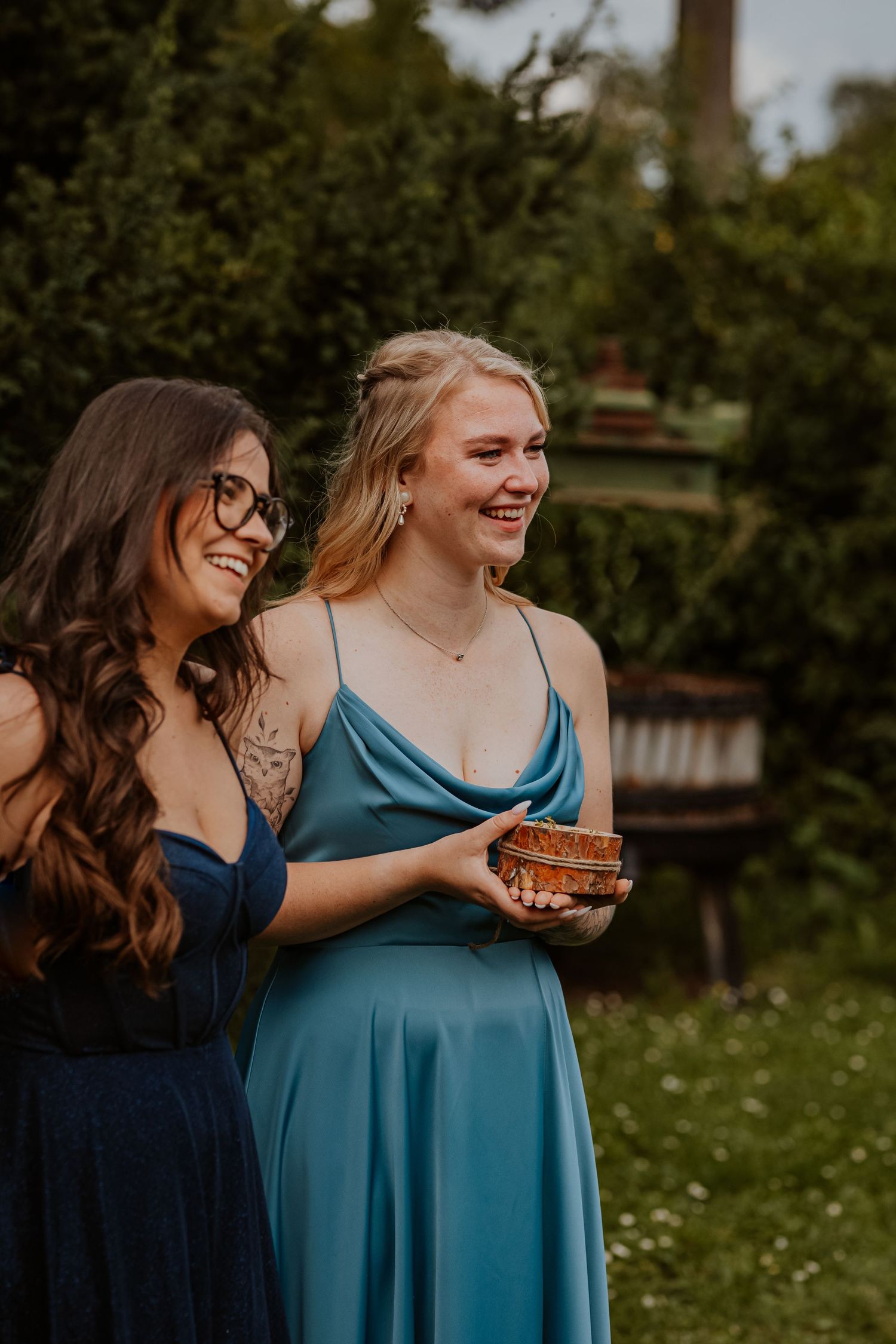 A romantic couple in white clothing shares an intimate moment in a wooded setting during golden hour.