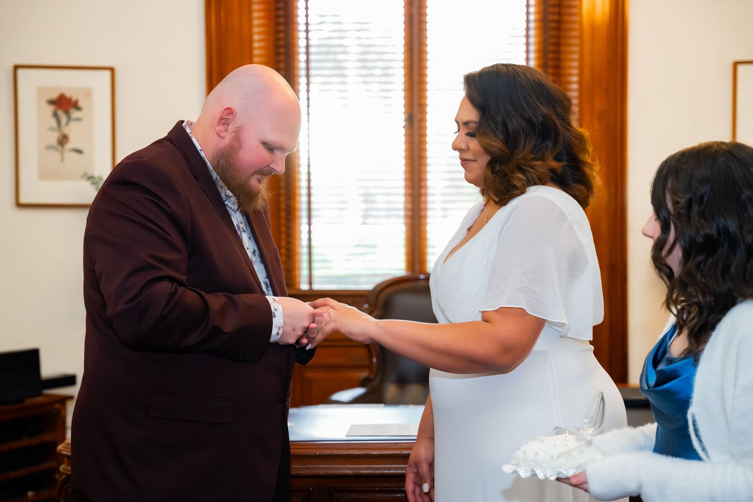 A couple exchanges rings during an intimate indoor wedding ceremony with wooden accents and natural lighting.