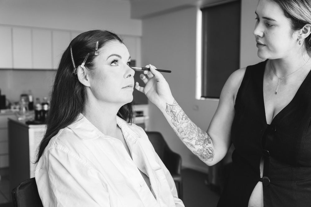 Black and white photo of wedding day preparation with makeup being applied.
