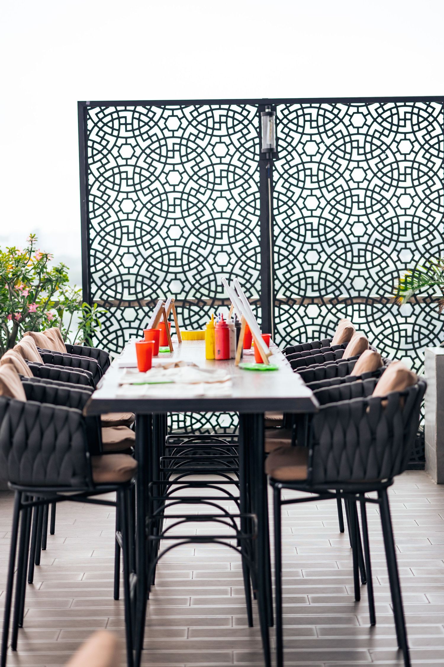 Modern outdoor dining area with geometric patterned dividers and black cushioned chairs.