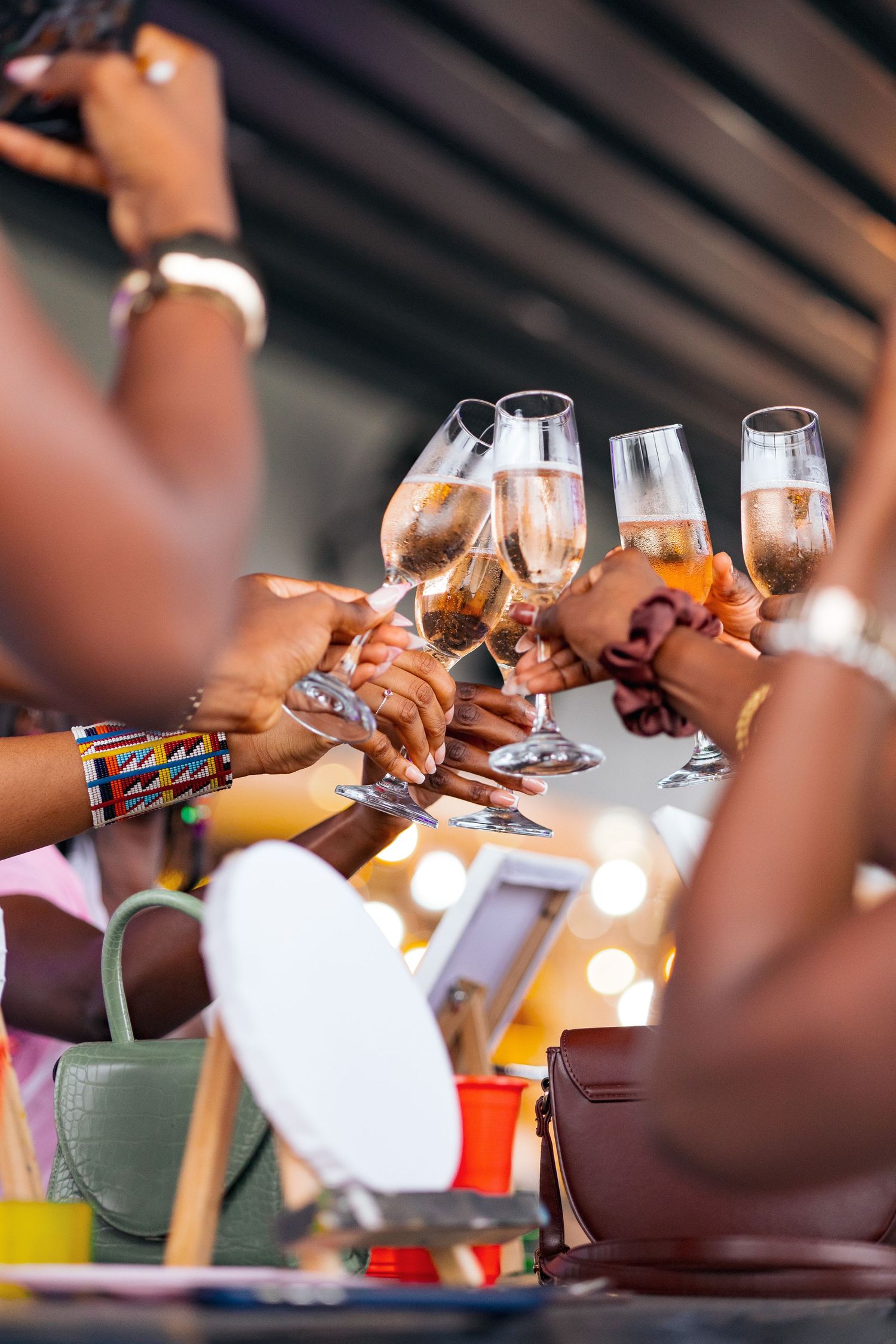 Hands raise champagne glasses for a toast during an art class gathering.