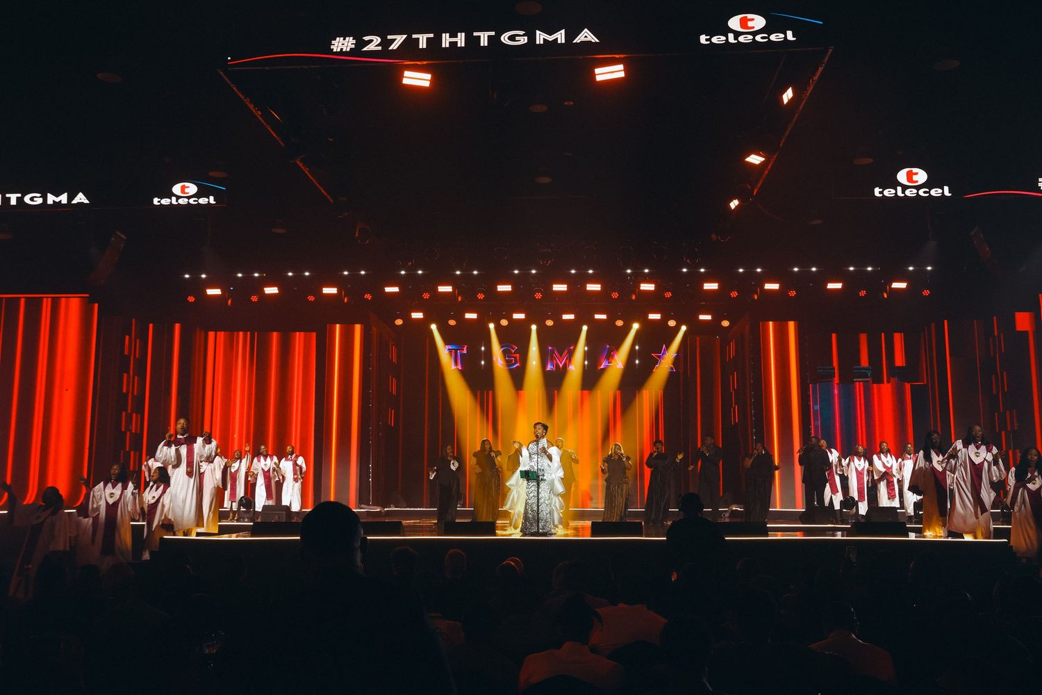 Performers on stage at the 27th TGMA awards ceremony with dramatic red and gold lighting backdrop.