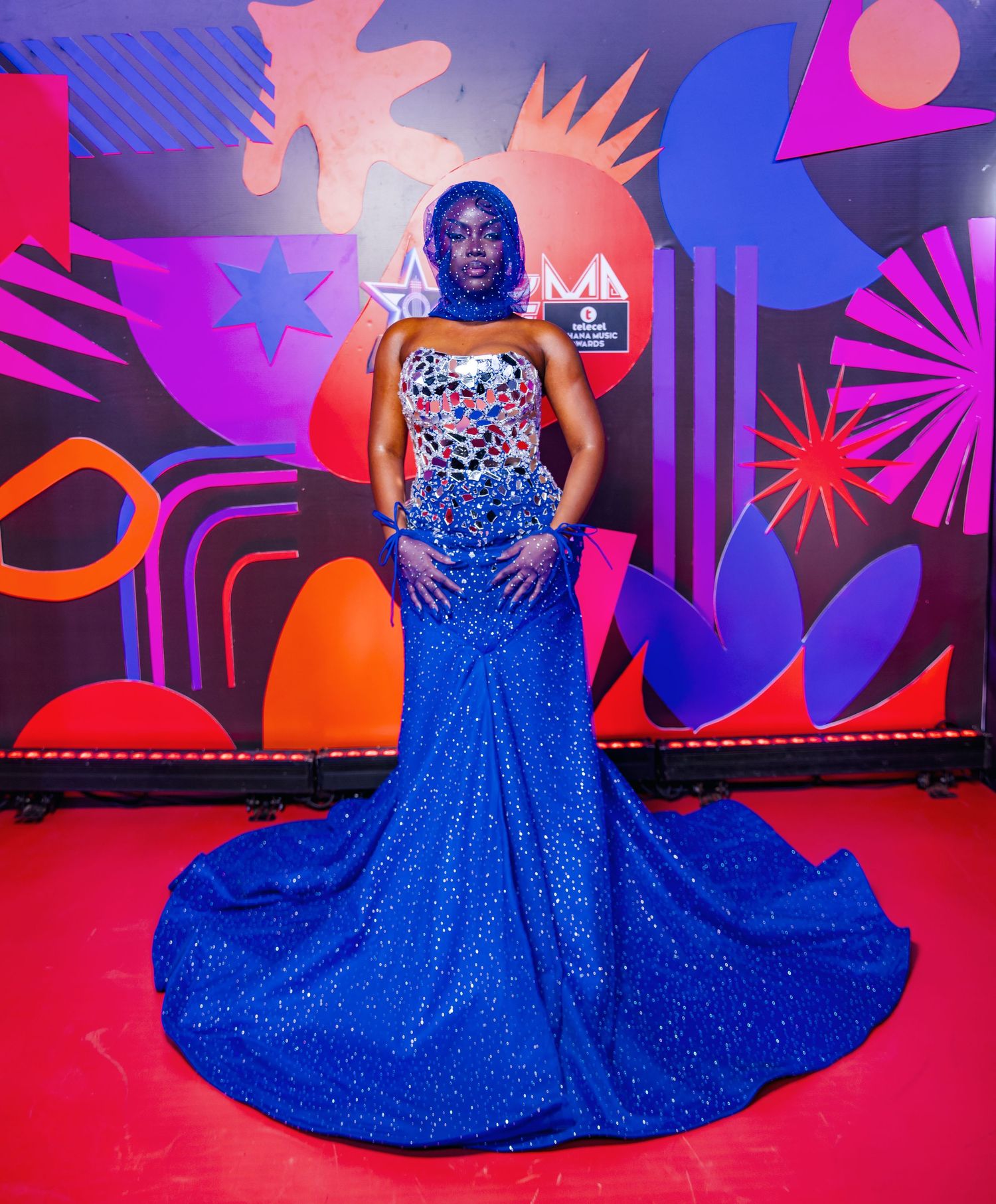 Woman in royal blue sequin gown with matching makeup poses at Telecel Ghana Music Awards.