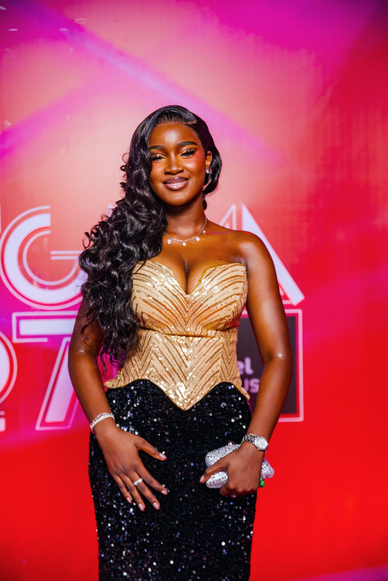 Woman in gold sequin corset and black gown posing on red carpet at GHANA awards event.