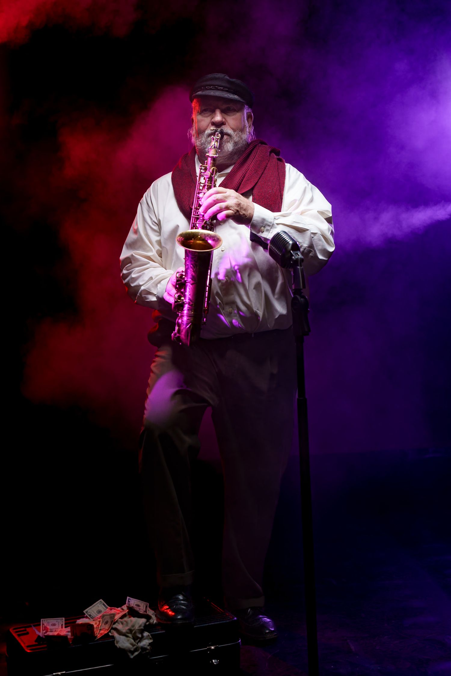 Saxophonist performing on stage with purple and red atmospheric lighting.