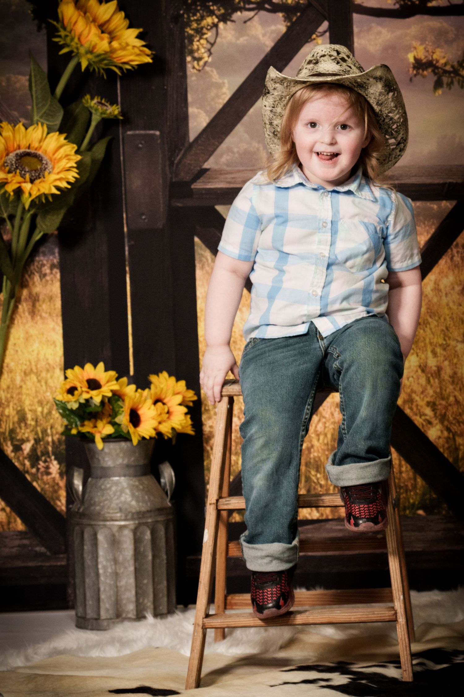 Rustic country scene with wooden ladder, faded backdrop and bright sunflowers in a vintage milk can.