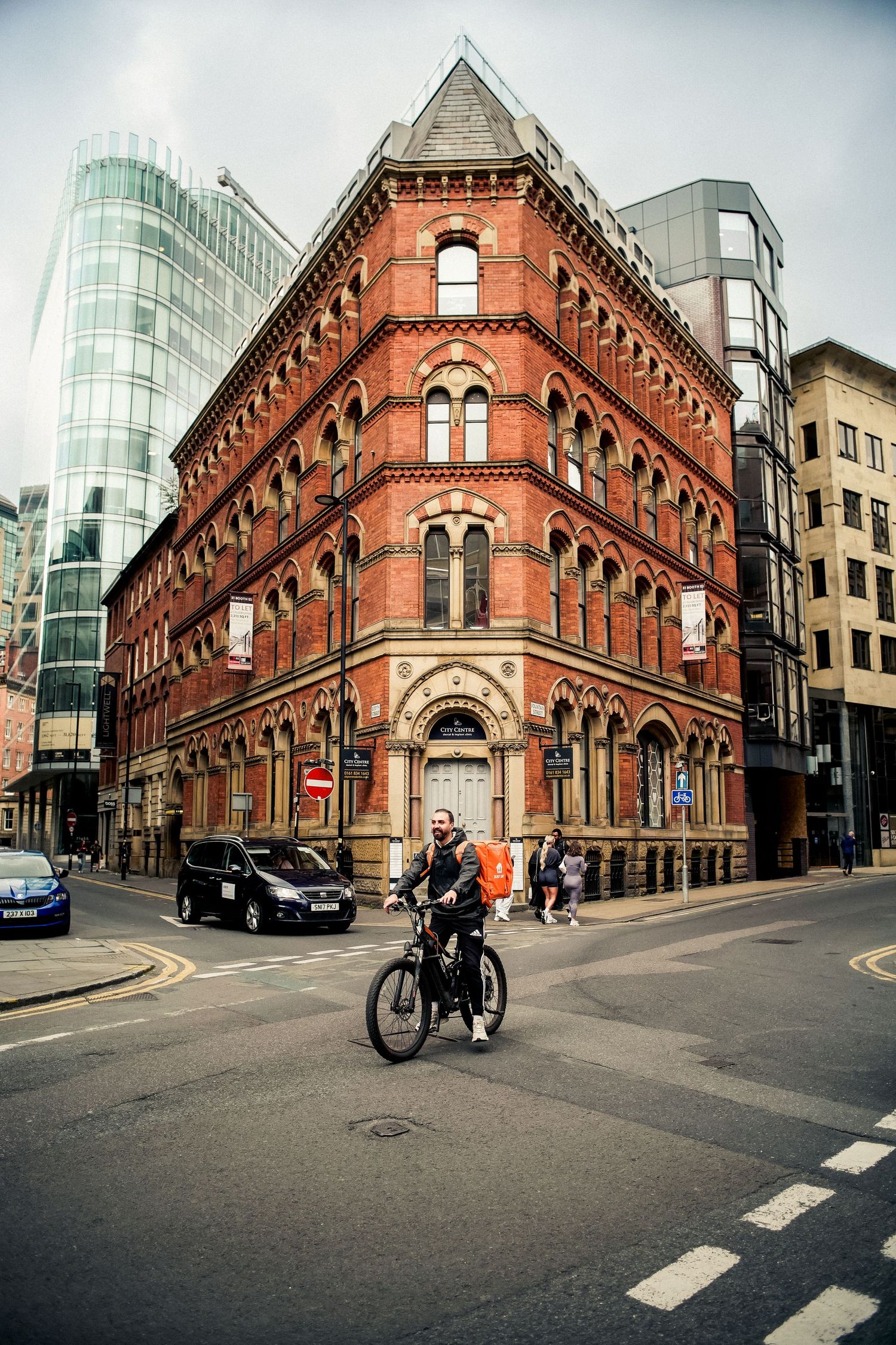 Historic red brick Victorian building with modern glass towers in the background.
