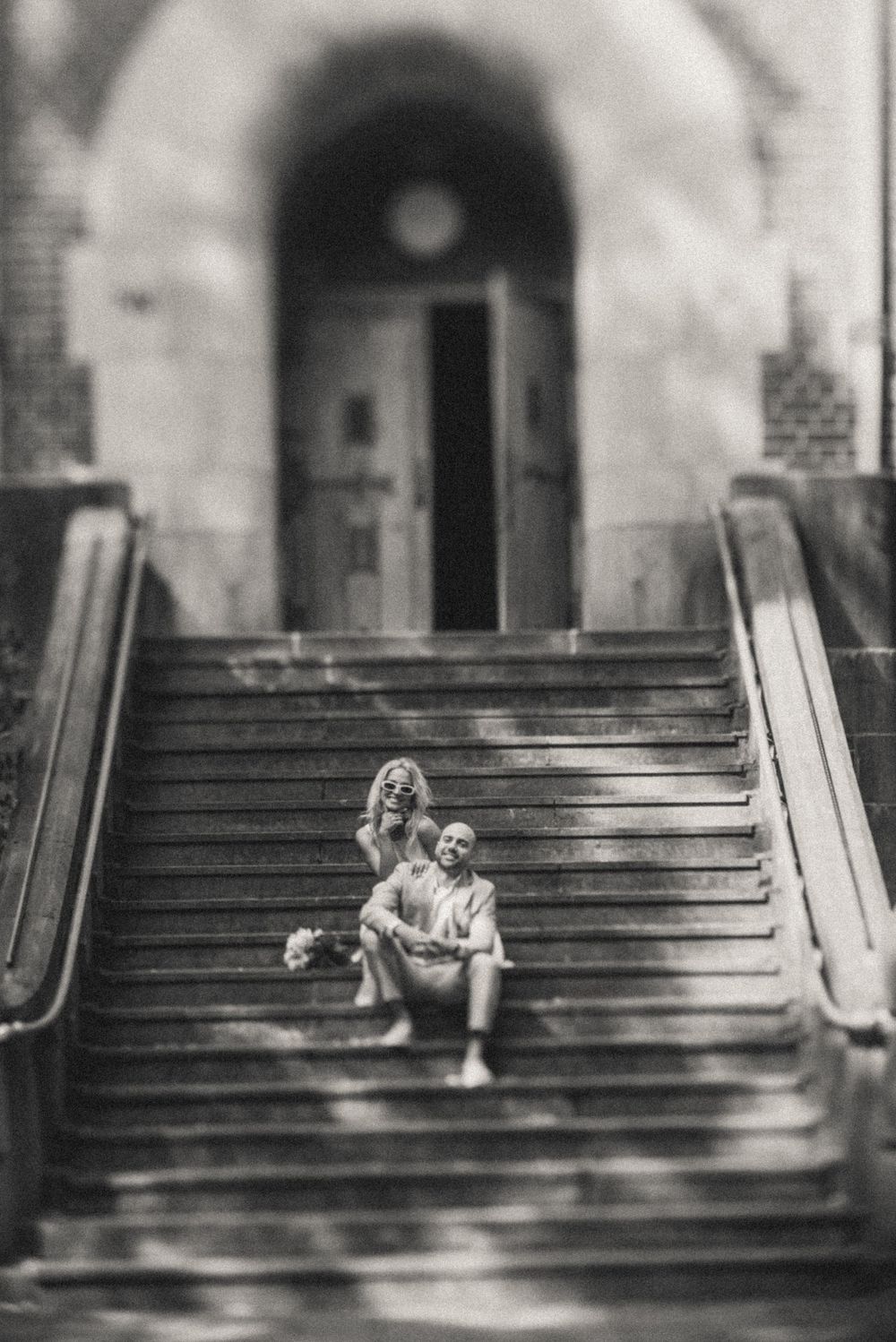 Black and white photo of people sitting on grand stone steps.