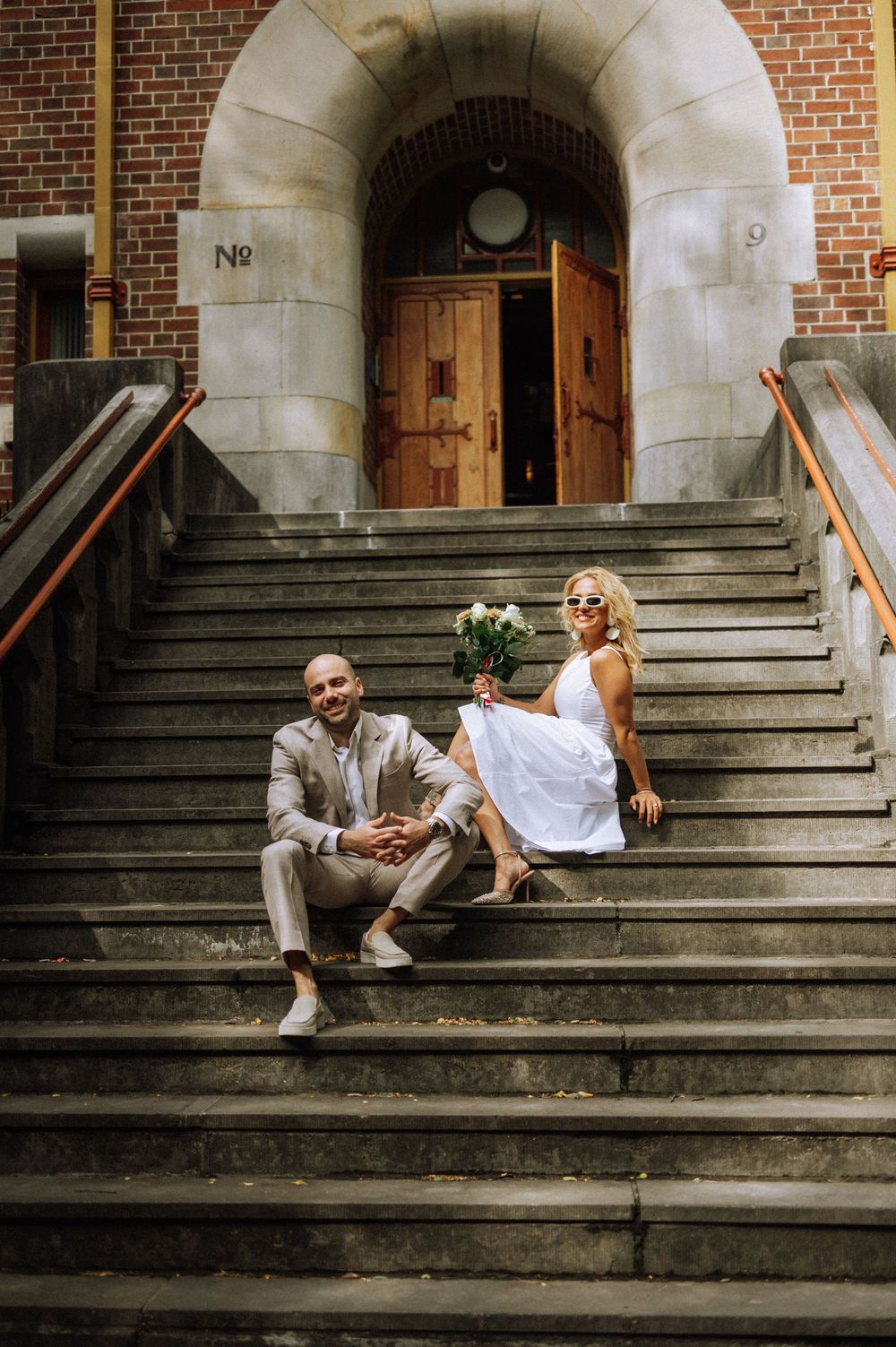 Couple relaxing on stone steps of historic building entrance.