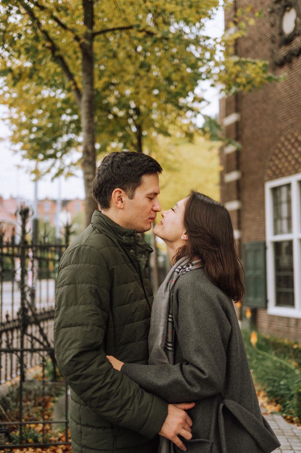 Couple sharing an intimate moment on a tree-lined street during fall season.