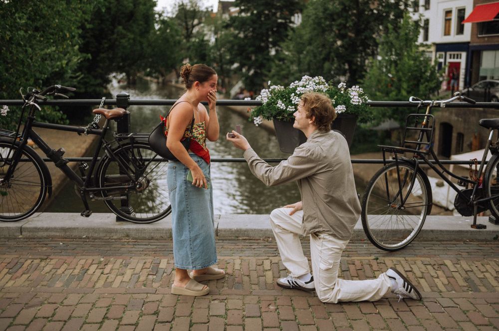 A couple relaxes on cobblestone streets with bicycles and string lights in Amsterdam.