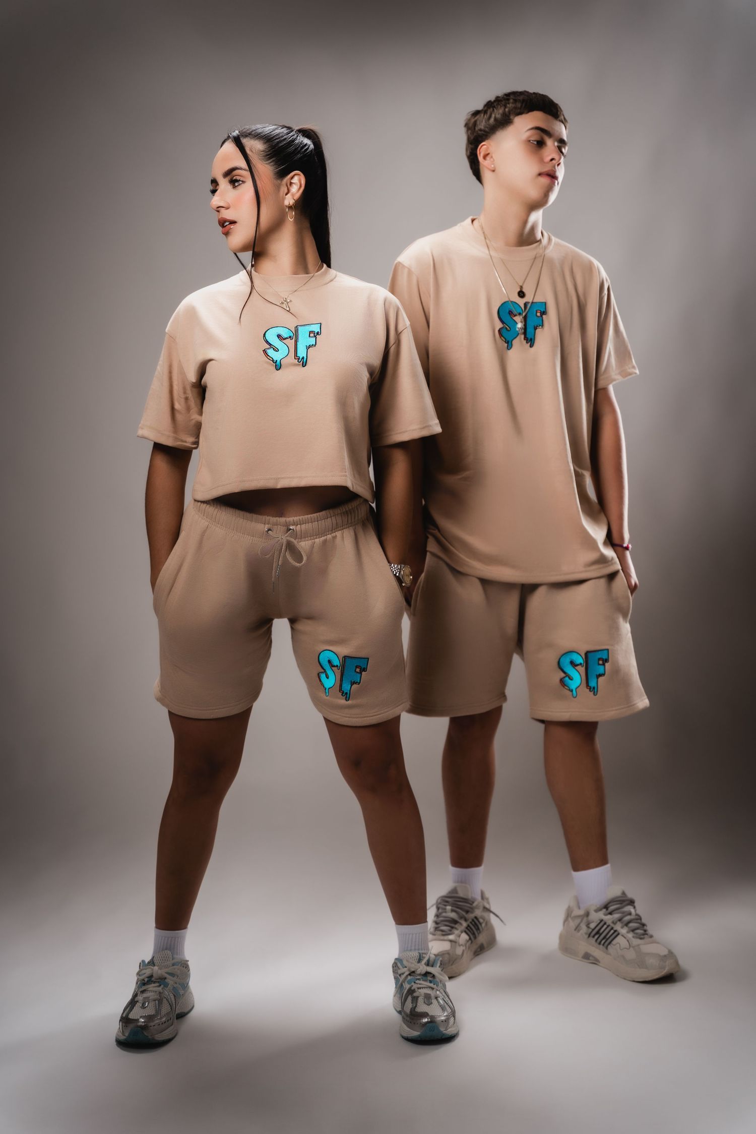 Two people in matching beige loungewear with blue butterfly designs pose against neutral background.