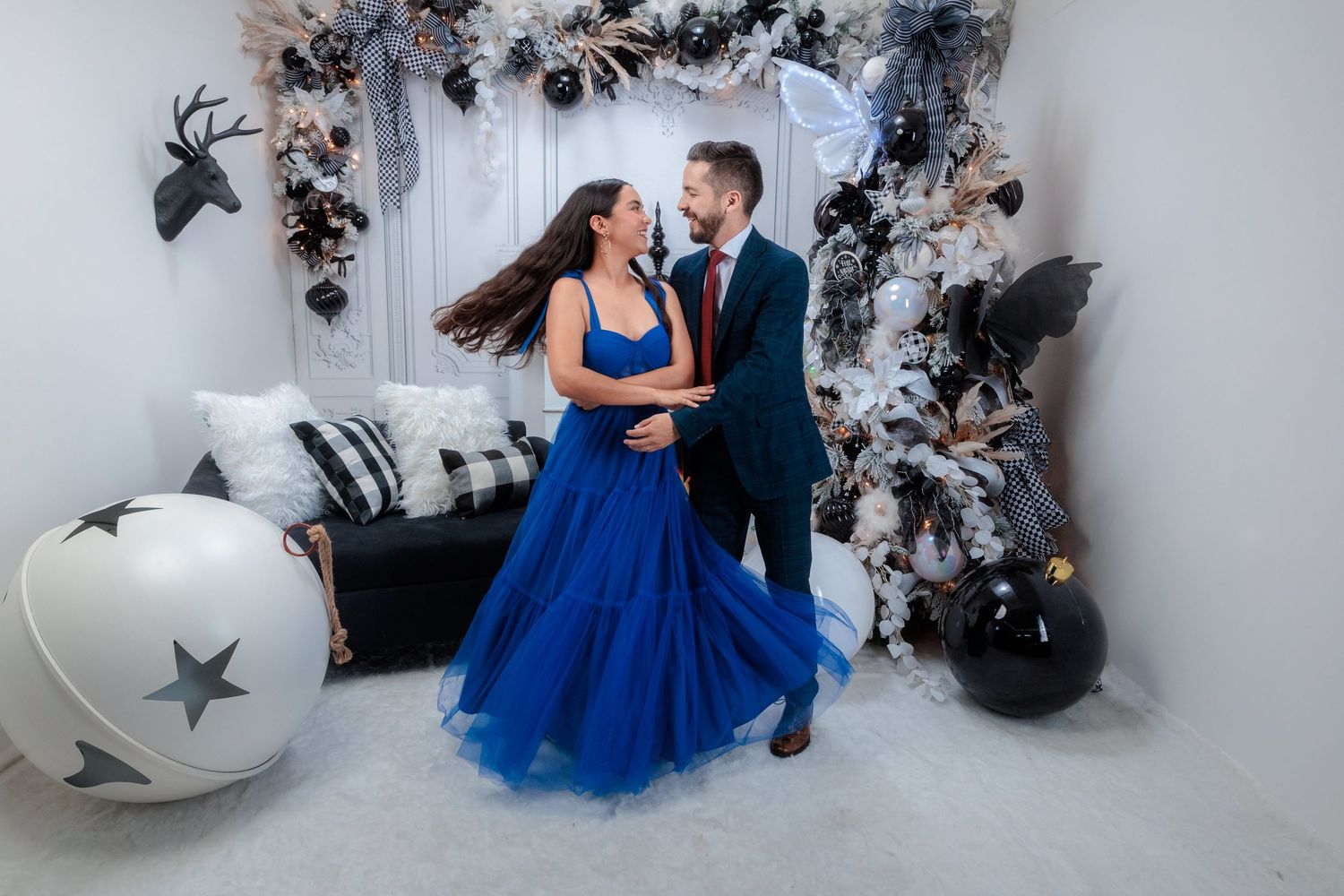Elegant holiday photoshoot with blue dress against white Christmas decorations and star props.