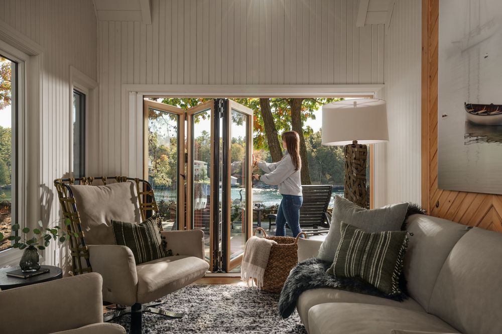 Bright living room with floor-to-ceiling windows overlooking outdoor pool area and comfortable seating.