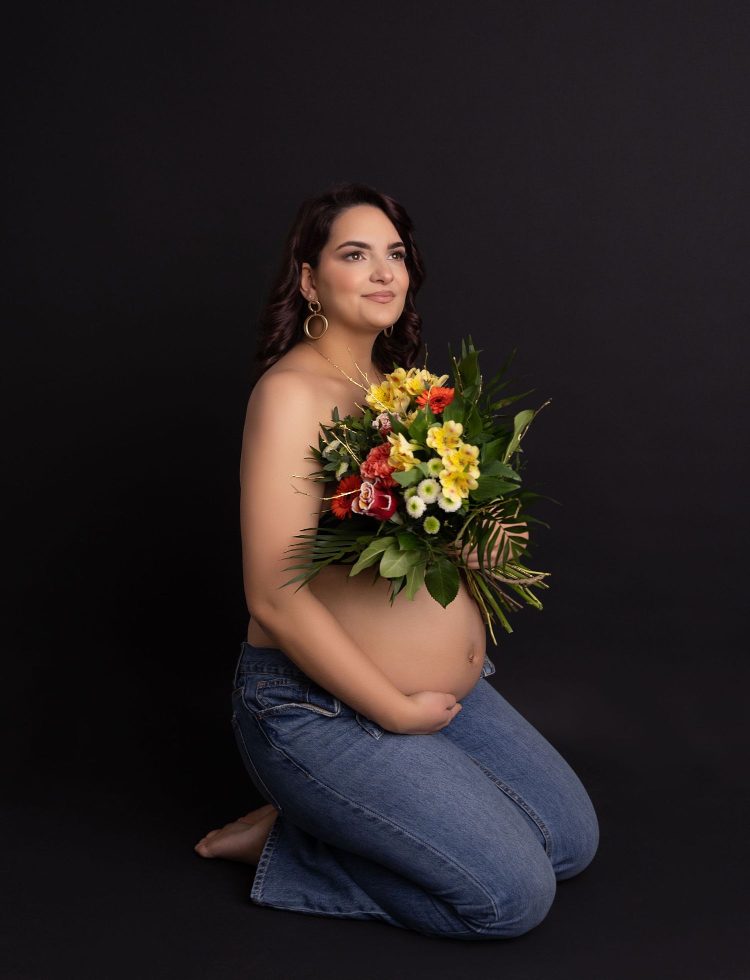 Artistic maternity photos with tropical flowers against dark background.