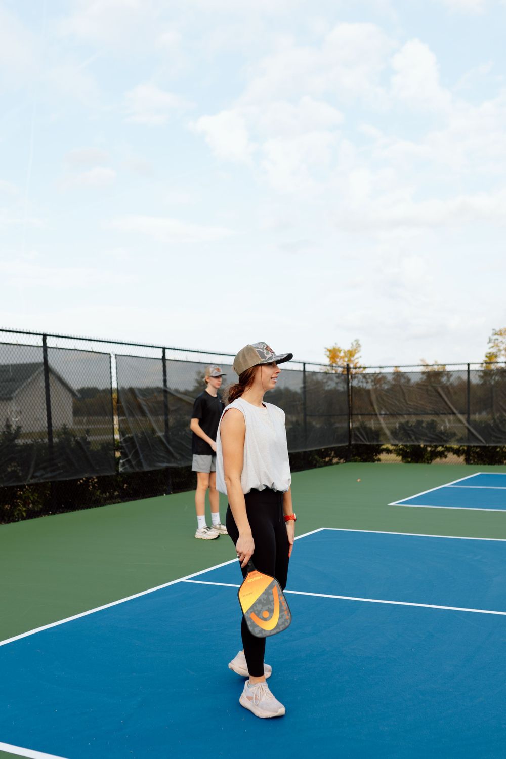 Two women playing pickleball on an outdoor blue court on a sunny day.