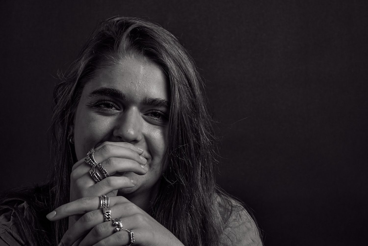 Zwart wit portret van een jonge vrouw met ringen om haar vingers