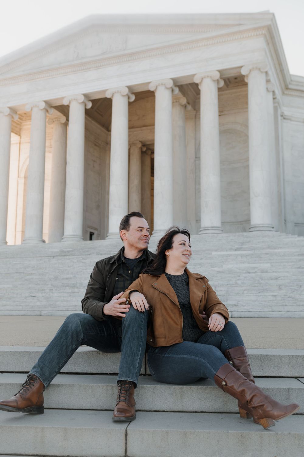 A couple relaxes on the steps of the Jefferson Memorial with its grand white columns.