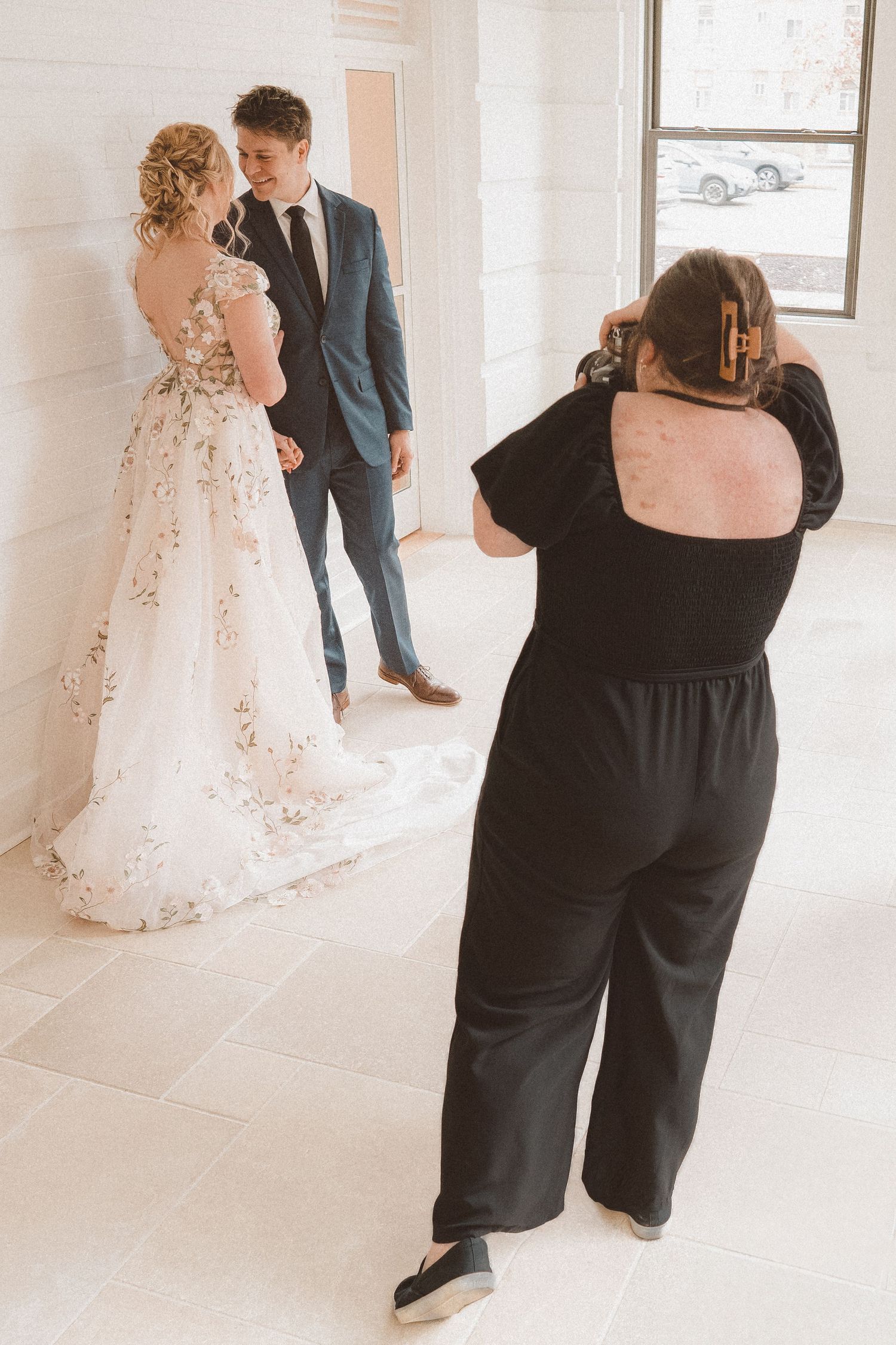 An image taken from behind a photographer who is taking photos of a couple on their wedding day.