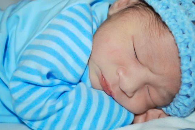 Sleeping newborn wrapped in blue and white striped blanket.