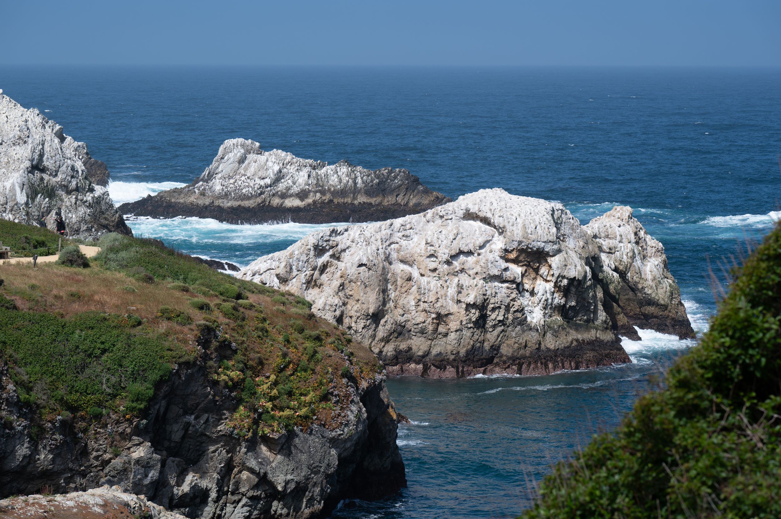 White limestone rock formations jutting out into blue ocean waters along a dramatic coastline.