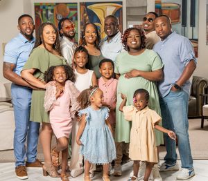 A group of people wearing coordinated pastel outfits pose together for a family portrait session.