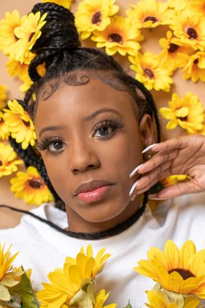 Portrait surrounded by bright yellow sunflowers against a white background creating a cheerful spring aesthetic.