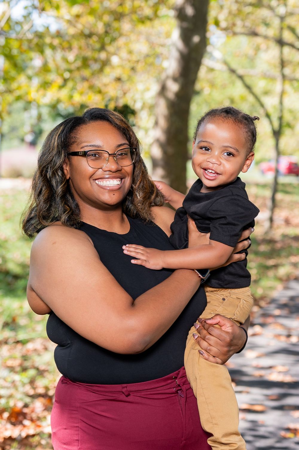 A joyful autumn photo session outdoors with mother and child wearing coordinated black and burgundy outfits.