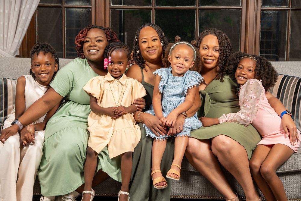 A group of people sitting together on a couch smiling and laughing while enjoying each other's company.