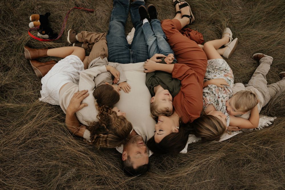 Aerial view of a family lying in a circle on dry grass, smiling and relaxing together amongst the scenic view of Albertas landscape