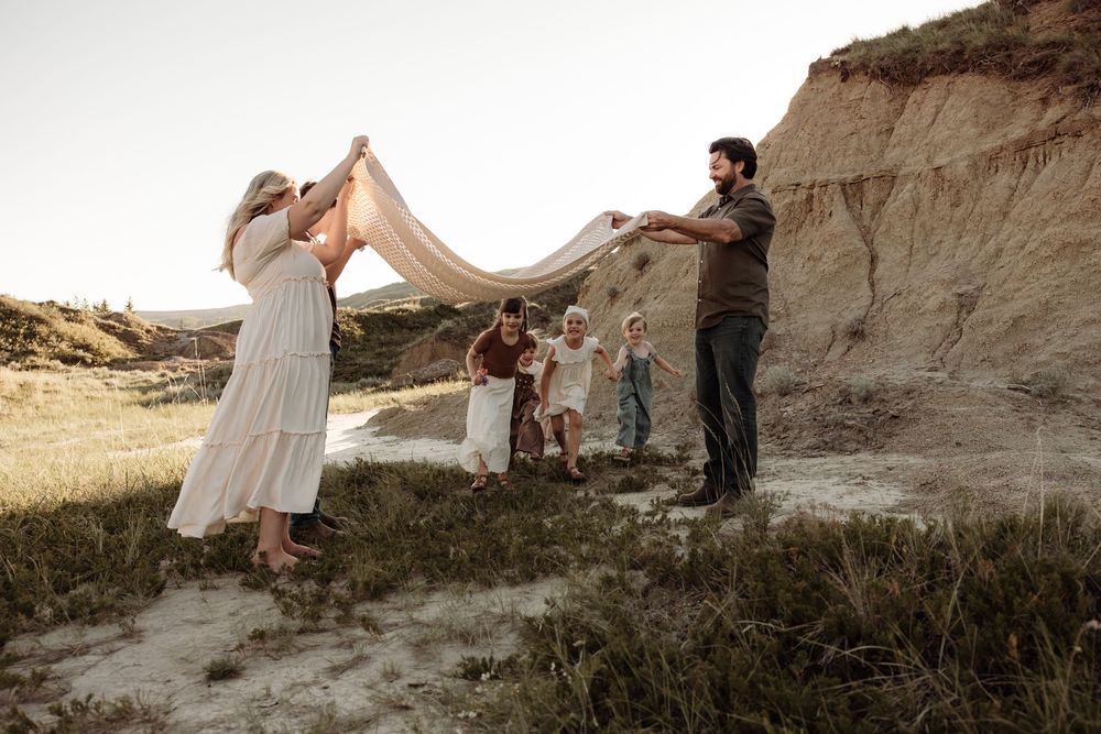 Family playing under a blanket during candid photos in alberta
